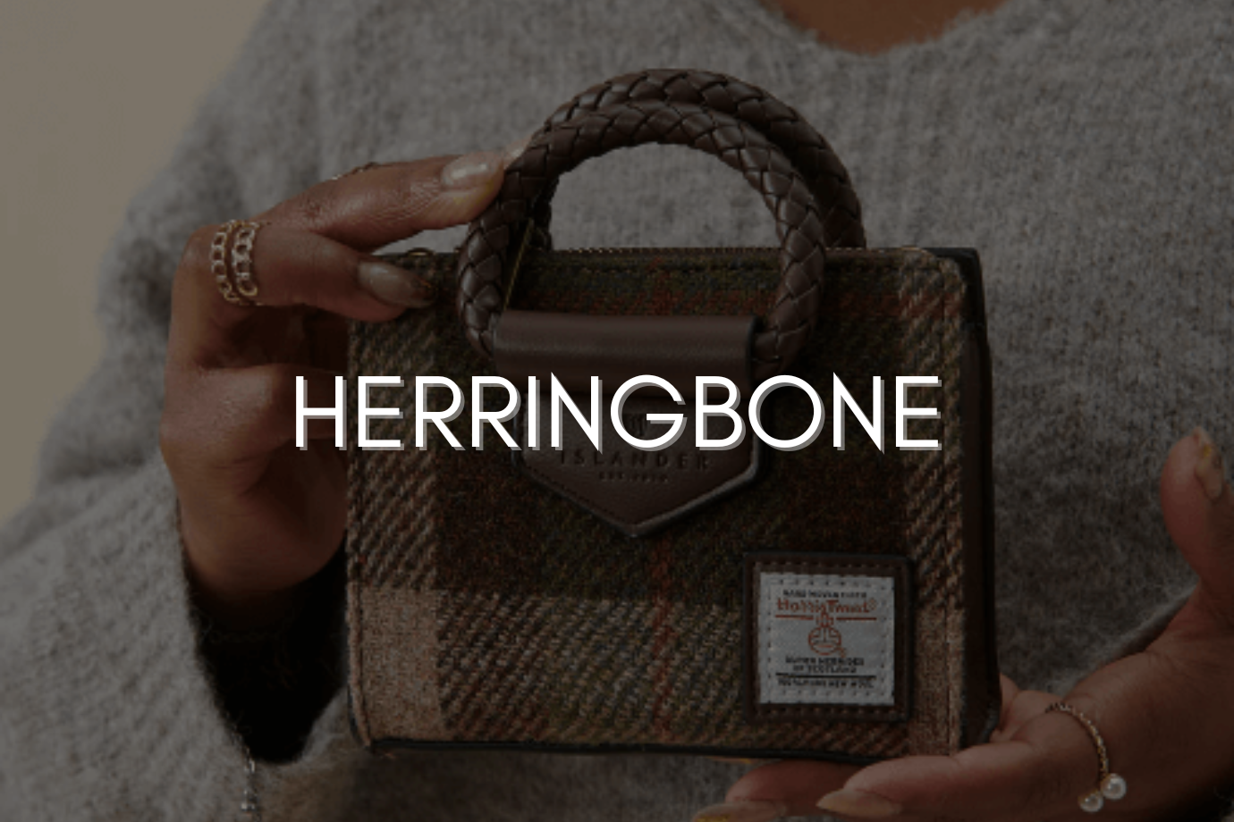 herringbone website cover image. Woman holding stylish bag.